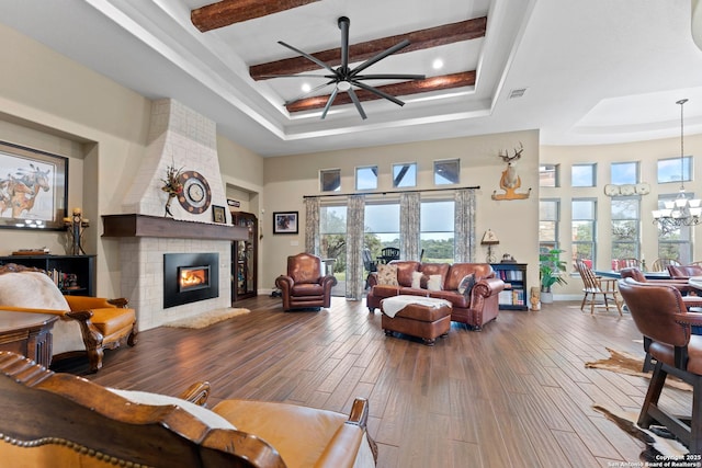 living room with a high ceiling, a fireplace, wood finished floors, baseboards, and beam ceiling