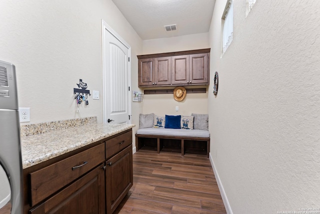 washroom with dark wood-style floors, visible vents, a textured wall, a textured ceiling, and baseboards