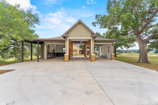 view of front facade with a shingled roof, concrete driveway, and stucco siding