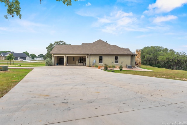 ranch-style home with central air condition unit, stucco siding, an attached garage, a front yard, and driveway