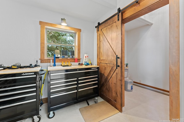 interior space featuring concrete flooring, light countertops, baseboards, and a barn door