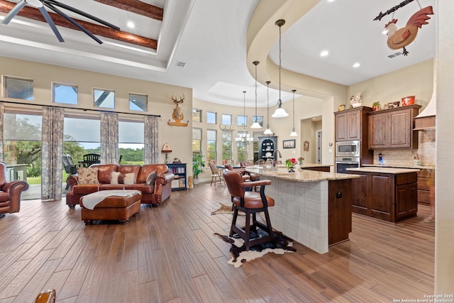 kitchen featuring an island with sink, a kitchen breakfast bar, open floor plan, hanging light fixtures, and stainless steel appliances