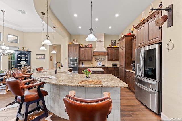 kitchen with a large island, a breakfast bar area, decorative light fixtures, stainless steel appliances, and a sink