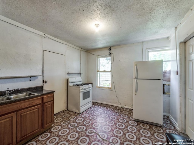 3315 Pitluk Ave, San Antonio, TX 78211 - kitchen with dark countertops, brown cabinetry, a sink, a textured ceiling, and white appliances