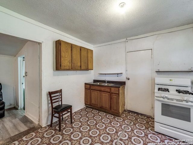 3315 Pitluk Ave, San Antonio, TX 78211 - kitchen featuring dark countertops, brown cabinets, white range with gas cooktop, and a sink