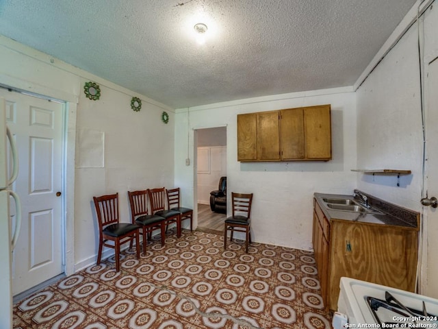3315 Pitluk Ave, San Antonio, TX 78211 - kitchen featuring brown cabinetry, light tile patterned flooring, a sink, and stove