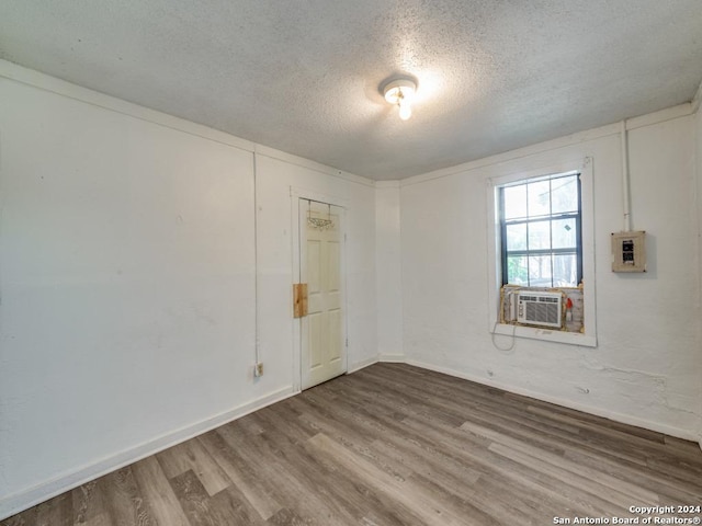 3315 Pitluk Ave, San Antonio, TX 78211 - empty room featuring electric panel, baseboards, wood finished floors, a textured ceiling, and cooling unit