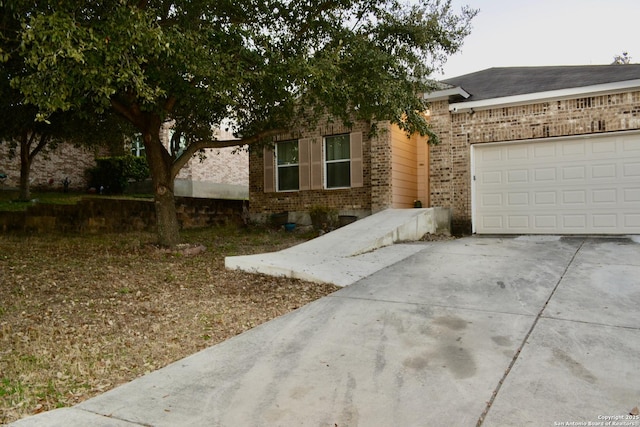 view of front of property featuring driveway, a garage, and brick siding