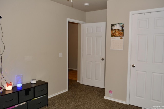 bedroom with dark carpet and baseboards