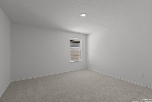 unfurnished room featuring light colored carpet, a textured ceiling, and baseboards