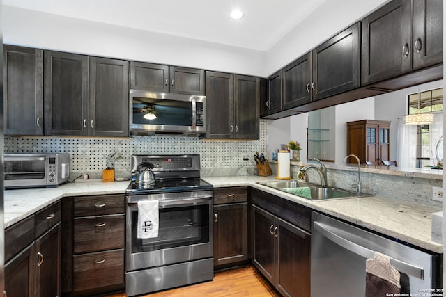 kitchen featuring appliances with stainless steel finishes, a toaster, a sink, and decorative backsplash