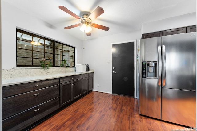 kitchen with ceiling fan, light stone counters, dark wood-type flooring, dark brown cabinets, and stainless steel refrigerator with ice dispenser