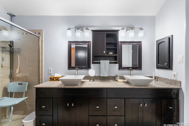 bathroom featuring double vanity, a shower stall, and a sink