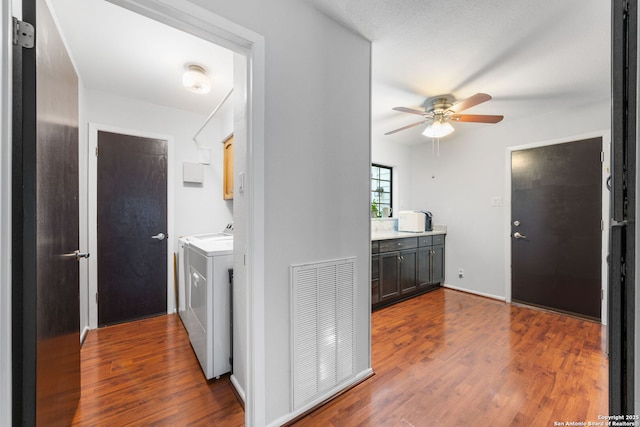 interior space with visible vents, washing machine and clothes dryer, wood finished floors, and cabinet space