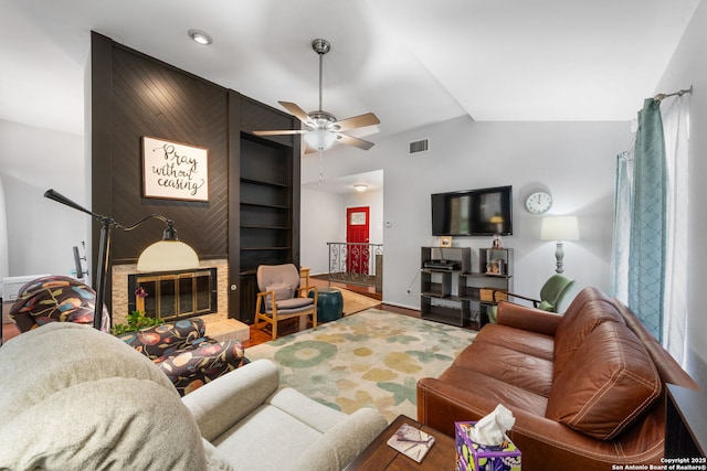 living room featuring a ceiling fan, lofted ceiling, a large fireplace, and visible vents