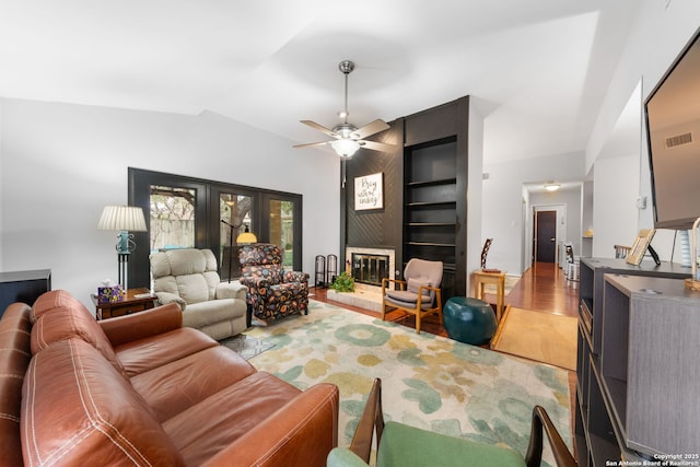 living room featuring a ceiling fan, lofted ceiling, a large fireplace, and wood finished floors