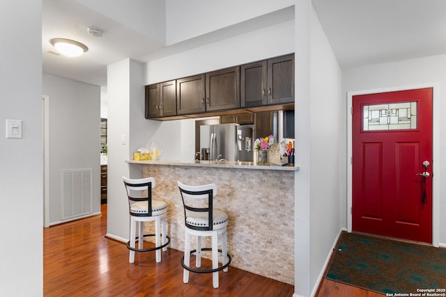 kitchen with visible vents, stainless steel fridge with ice dispenser, dark wood-style flooring, light countertops, and dark brown cabinets