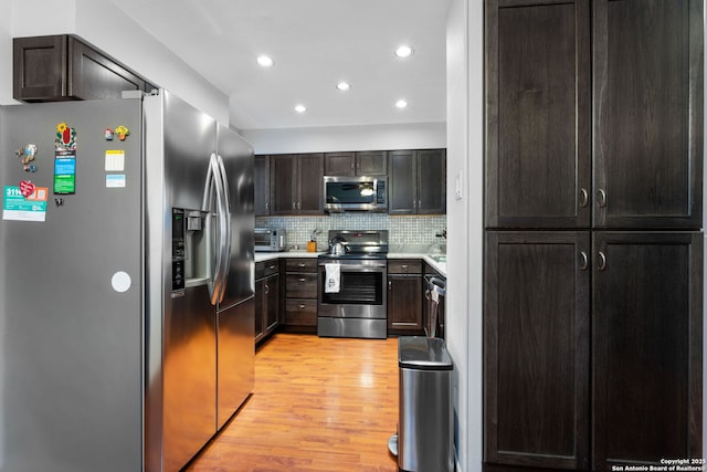 kitchen with recessed lighting, stainless steel appliances, light countertops, light wood-type flooring, and decorative backsplash