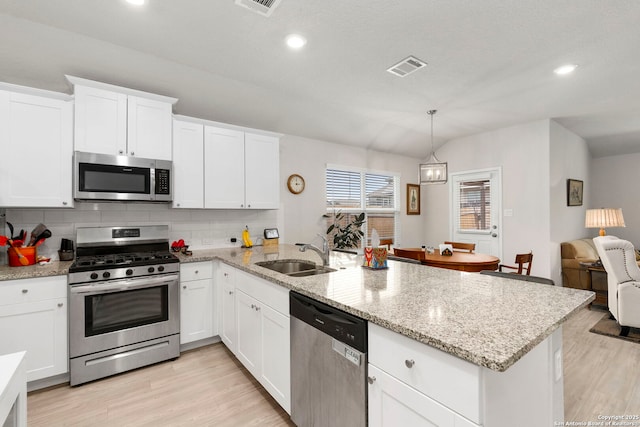 kitchen featuring white cabinets, pendant lighting, stainless steel appliances, and a sink