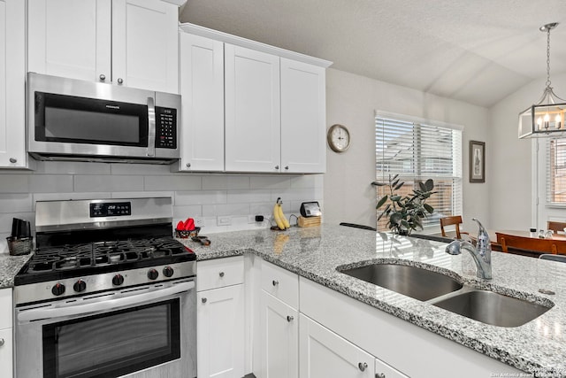 kitchen featuring hanging light fixtures, white cabinetry, appliances with stainless steel finishes, and a sink