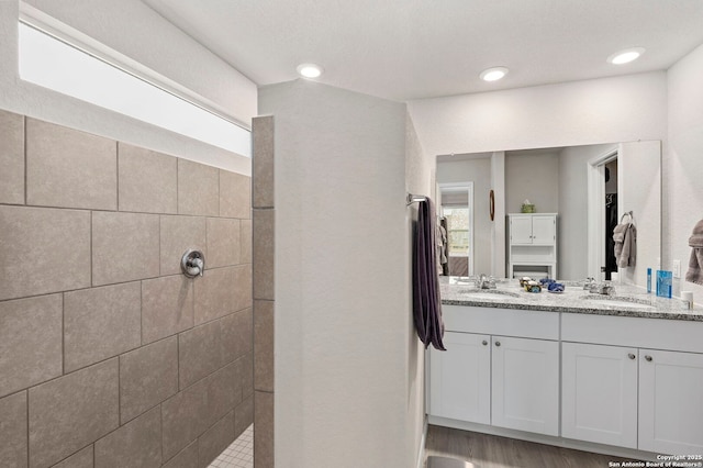 bathroom with double vanity, a sink, a spacious closet, and a walk in shower