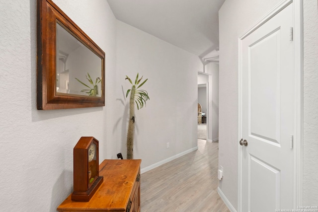 corridor featuring light wood-type flooring and baseboards