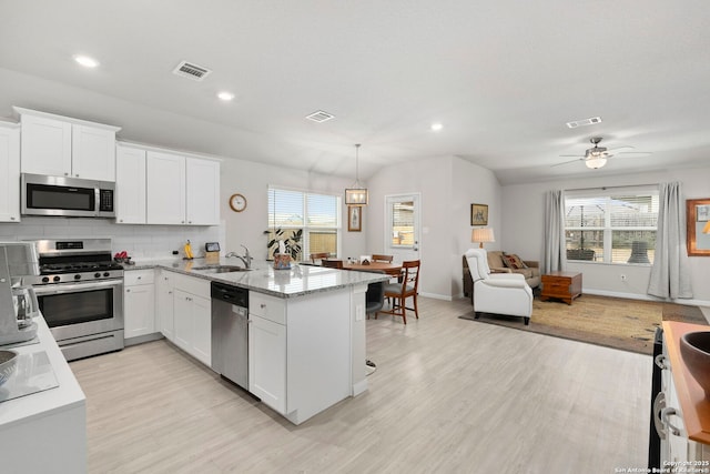 kitchen with stainless steel appliances, white cabinetry, hanging light fixtures, and visible vents