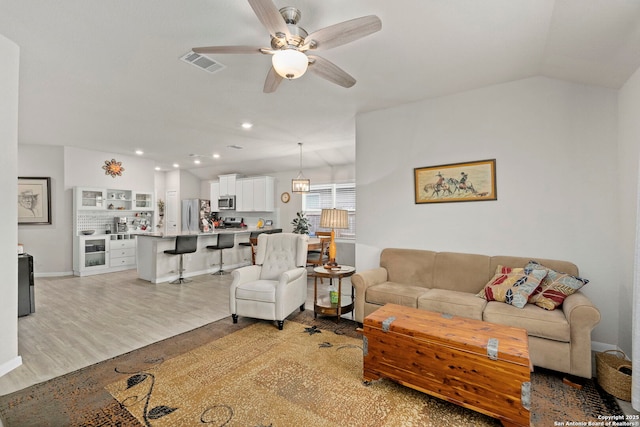 living area featuring ceiling fan, recessed lighting, visible vents, vaulted ceiling, and light wood finished floors