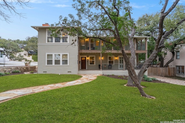 view of front facade with a chimney, stucco siding, a front yard, crawl space, and fence