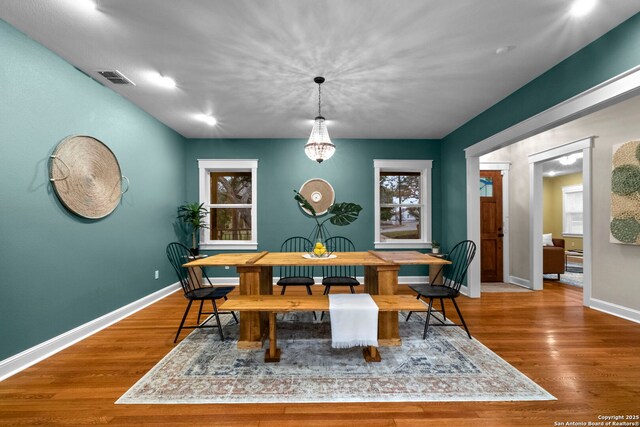 dining space featuring visible vents, baseboards, and wood finished floors