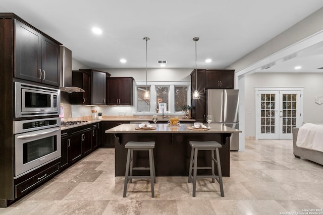 kitchen with appliances with stainless steel finishes, a center island, french doors, and pendant lighting