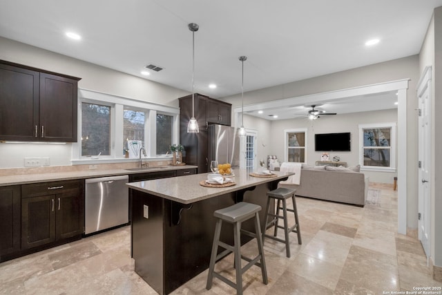 kitchen with visible vents, a breakfast bar area, hanging light fixtures, stainless steel appliances, and a sink