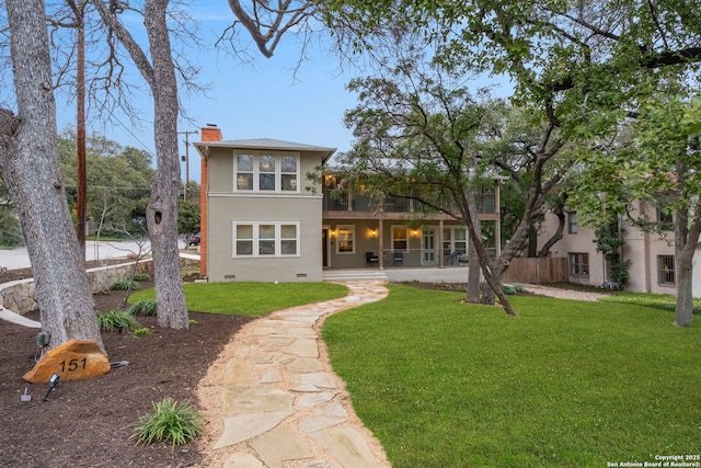 rear view of property featuring a chimney, crawl space, fence, a yard, and stucco siding