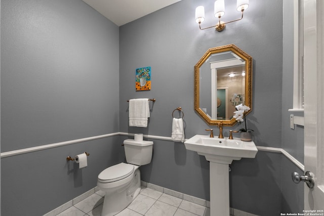 bathroom featuring tile patterned flooring, baseboards, and toilet