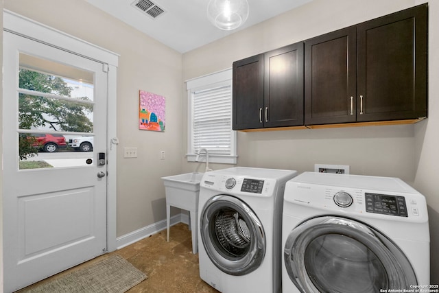 laundry area featuring washer and dryer, cabinet space, visible vents, and baseboards