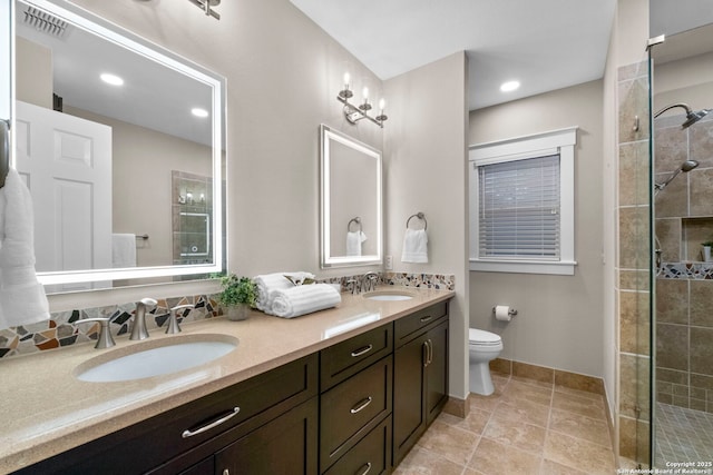 bathroom with a tile shower, double vanity, a sink, and visible vents