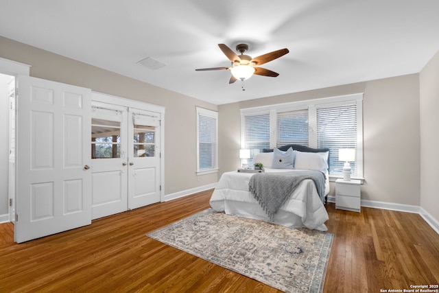 bedroom with ceiling fan, wood finished floors, and baseboards