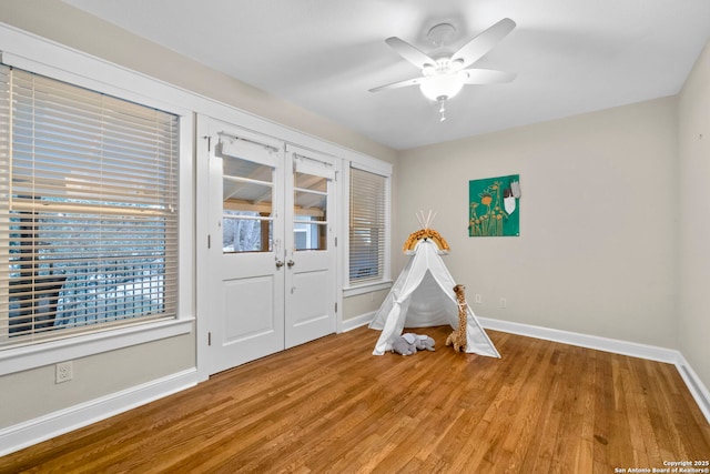 playroom featuring ceiling fan, baseboards, and wood finished floors