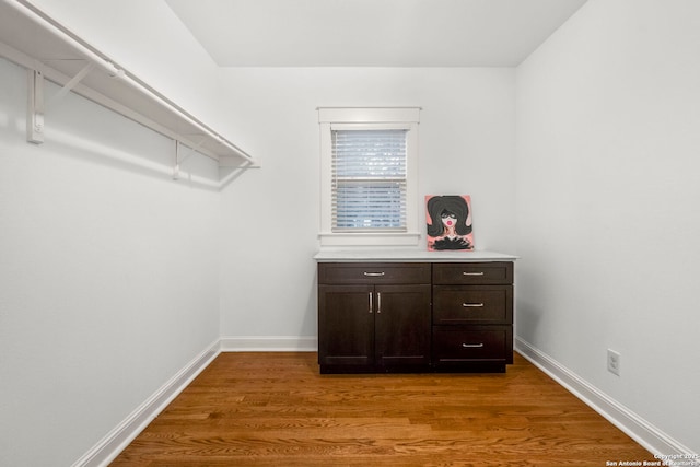 walk in closet with wood finished floors