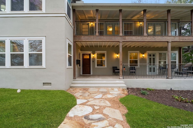 view of exterior entry with crawl space, a patio, and stucco siding