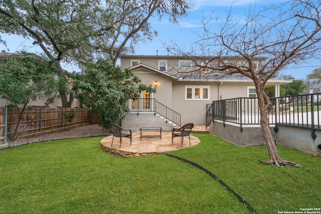 back of house featuring a yard, a patio, fence private yard, and stucco siding