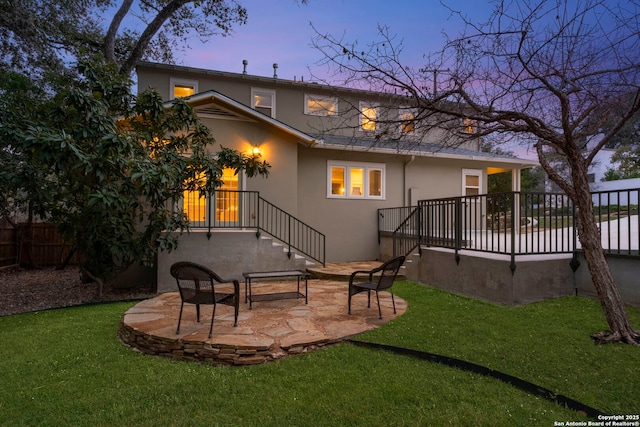 back of property featuring fence, a patio, a lawn, and stucco siding