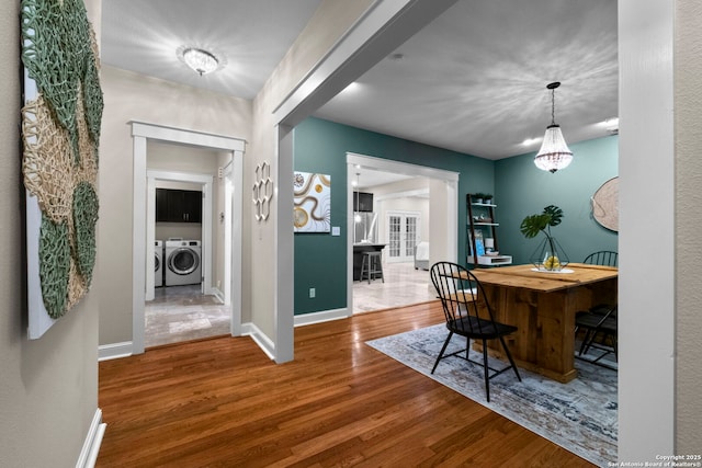 dining area featuring washing machine and dryer, baseboards, and wood finished floors