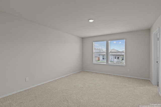 empty room featuring light colored carpet and baseboards