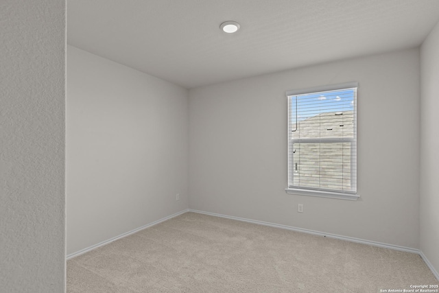 empty room featuring light colored carpet and baseboards