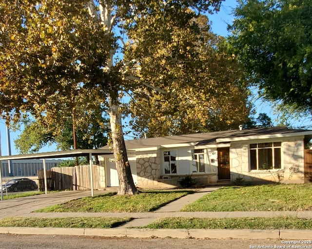 single story home featuring stone siding, a front lawn, and fence