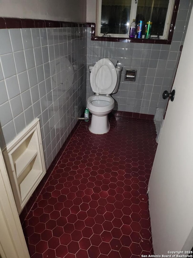 bathroom featuring tile patterned flooring, tile walls, and toilet