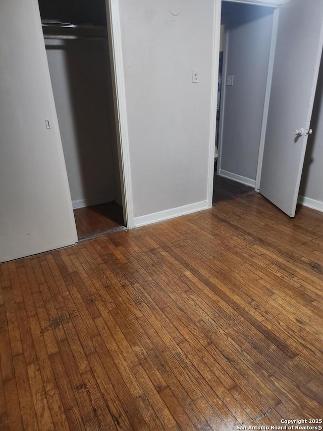 unfurnished bedroom with dark wood-style floors, a closet, and baseboards