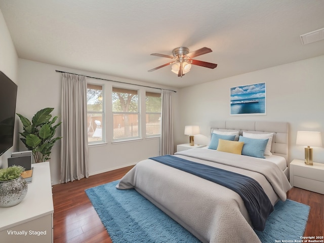 bedroom with ceiling fan, visible vents, and dark wood-type flooring