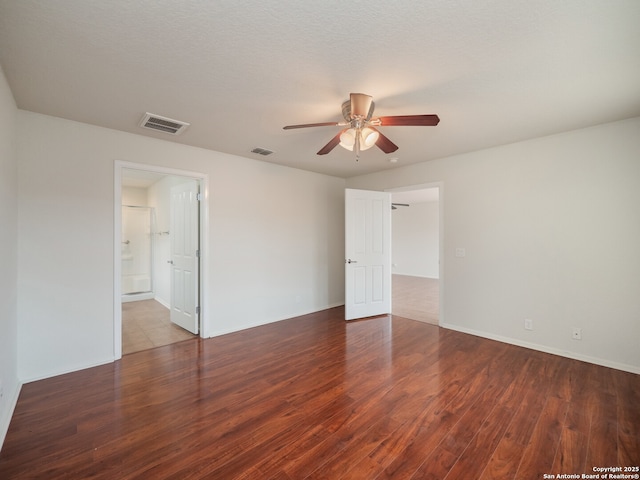 empty room featuring dark wood-style floors, ceiling fan, and visible vents